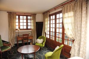 uma sala de estar com cadeiras verdes, uma mesa e janelas em Auberge De L'abbaye em Signy-lʼAbbaye