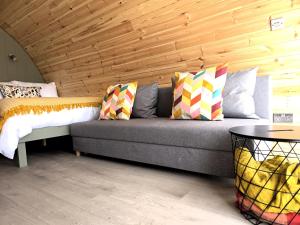 a couch in a room with a wooden wall at Nádúr Pods in Killarney, Co Kerry