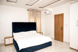 a bedroom with a bed with a blue headboard and a door at 3bedroom duplex with ps5 in Ikate, lekki phase 1 in Lekki
