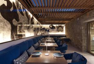 a dining room with tables and blue chairs and a wall at Amyth of Mykonos Super Paradise in Super Paradise Beach