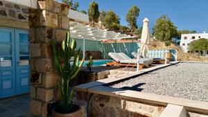 a patio with an umbrella and chairs and a pool at Theologos Houses in Grikos