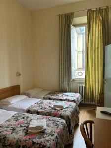 a hotel room with two beds and a desk at Hotel Liberty in Montecatini Terme