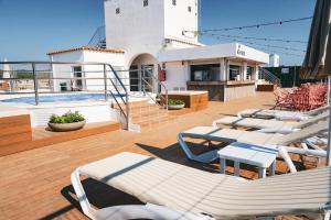 a deck with lounge chairs and a pool on a building at htop Amatista #htopBliss in Lloret de Mar