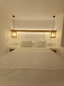 a white bed with two lights on top of it at Yialos Ios Hotel in Ios Chora