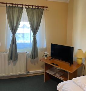 a bedroom with a television on a desk and a window at Flamingó Szállás in Kiskunmajsa
