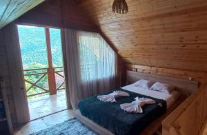 una camera da letto con un letto in una cabina di legno di House in the clouds&სახლი ღრუბლებში a Kʼveda Chʼkhutunetʼi
