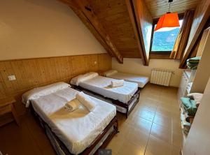 a room with three beds and a window at Hotel Taüll in Pla de l'Ermita
