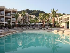 a pool at a hotel with palm trees and buildings at Admiral De Luxe in Zakynthos