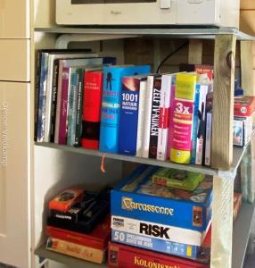 a book shelf filled with books next to a microwave at Rust en Natuur in Ons Vrijstaande Fins Chalet in Epe