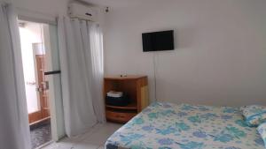 a bedroom with a bed and a flat screen tv at Hospedagem Rosa Branca in Uberlândia +9 photos