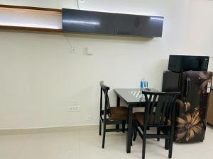 a kitchen with a table and two chairs and a refrigerator at Olive Service Apartments Hitech City in Hyderabad