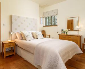 a bedroom with a large white bed and a mirror at The Granary at Cornish Barn Holidays in Truro