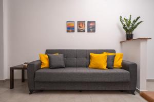 a gray couch with yellow pillows in a living room at Viola Apartment in Kissamos +10 photos