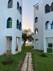 a white building with a grass yard next to it at Puesta Del Sol in Asilah