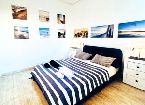 a bedroom with a bed with striped sheets and pictures on the wall at Chambre vue mer dans Villa à la Marina in Alicante