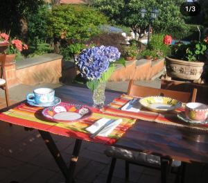 una mesa con platos y un jarrón de flores. en B&B Villa La Castagnola, en Rocca di Papa