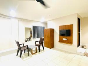 a living room with a table and chairs and a tv at Hotel Royal Orbit in Rajkot