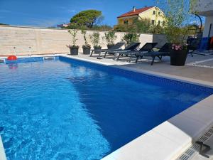 a swimming pool with blue water in a yard at Rimac Apartments in Novalja