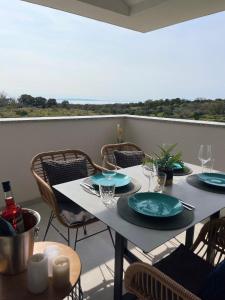 a table with plates and wine glasses on a balcony at Rimac Apartments in Novalja