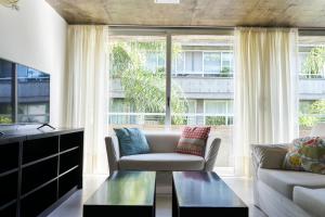 a living room with a couch and a large window at CINCO - Departamentos in La Plata