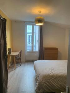 a bedroom with a bed and a desk and a window at Maison Frères Prêcheurs in La Rochelle