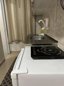 a white kitchen with a sink and a stove at Kitnet 301 centro linda vista por sol com tv smart e ar in Montes Claros