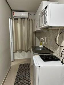 a small kitchen with a stove and a microwave at Kitnet 301 centro linda vista por sol com tv smart e ar in Montes Claros