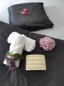 ミッデルケルケにあるResidentie Luminaのベッドの上にタオルと花、そしてメモ