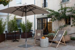 a patio with two chairs and an umbrella at Le Saint-Nicolas H&ocirc;tel in La Rochelle