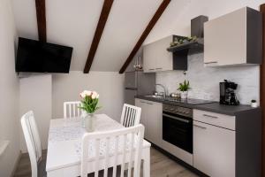 a kitchen with white cabinets and a table with chairs at Apartman Malnar Lokve in Lokve