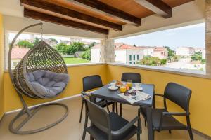 a balcony with a table and chairs and a swing at Apartments Bellissima in Funtana