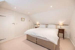 a white bedroom with a large bed with white sheets at 10 Angel Lane, Woodbridge in Woodbridge