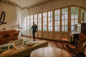 a man walking through a living room with large windows at Viajero Montevideo Hostel in Montevideo