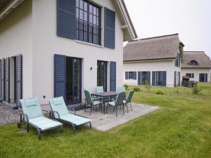 eine Terrasse mit Stühlen und einem Tisch vor einem Haus in der Unterkunft Reetland am Meer - Superior Reetdachvilla mit 2 Schlafzimmern F02 in Dranske