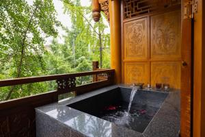 a bath tub with a water fountain in front of a window at 青城山泉青小院温泉中式民宿 in Taiping