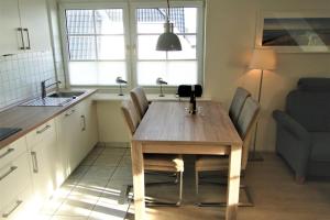 a kitchen with a wooden table with chairs and a sink at Thora Jaiken Hüs Thora Jaiken, Apart Anneke in Rantum