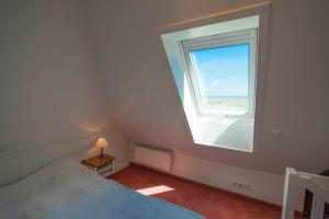 Un dormitorio con una cama y una ventana grande. en Warfthüs, App 5, en Rantum