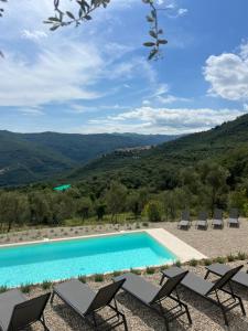 a pool with chairs and a view of mountains at Tipì Terra in Chiusanico