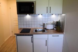 a kitchen with white cabinets and a sink at Thora Jaiken Hüs Thora Jaiken, Apart Birthe in Rantum