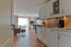a kitchen with white cabinets and a tile floor at Landhaus auf der Düne, App 2 in Rantum +9 photos