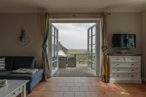 a living room with a couch and a sliding glass door at Landhaus auf der Düne, App 2 in Rantum