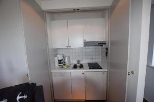 a small kitchen with white cabinets and a sink at Friesenhof, fr 02 in Rantum +1 photo