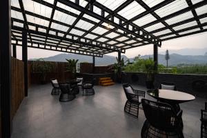 a patio with chairs and tables and a pergola at 青城山泉青小院温泉中式民宿 in Taiping