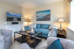 Godewind Haus Godewind, GO02 في رانتوم: غرفة معيشة مع أريكة زرقاء وطاولة