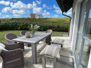 a wooden table and chairs on a patio with a view at Strandhaus in Rantum
