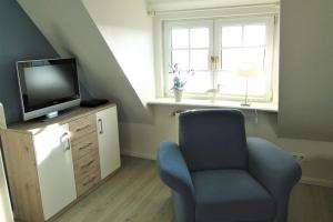 Una sala de estar con una silla y un televisor. en Thora Jaiken Hüs Thora Jaiken, Apart Eike, en Rantum