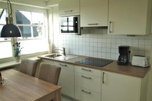 Una cocina con gabinetes blancos y una encimera de madera. en Thora Jaiken Hüs Thora Jaiken, Apart Eike, en Rantum