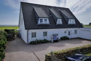 una casa blanca con techo negro en Thora Jaiken Hüs Thora Jaiken, Apart Eike, en Rantum