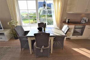 a kitchen with a table with chairs and a window at Heefkant Haus Heefkant, HK 04 in Rantum +5 photos