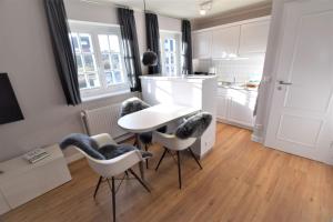 a kitchen with a white table and chairs in a room at Warfthüs App 08 in Rantum